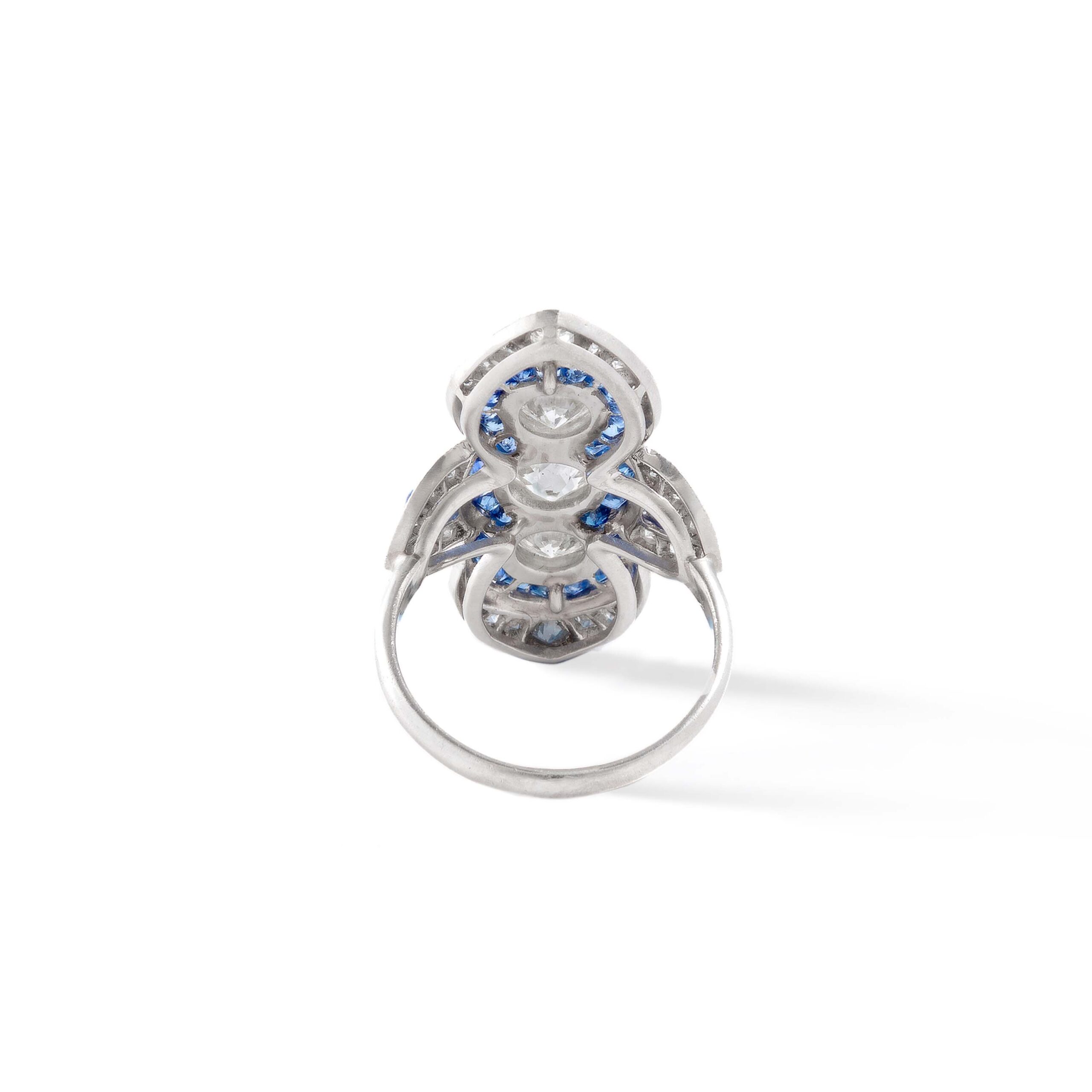 Art Deco Three Stones Diamond surrounded by calibrated Sapphire on Platinum Ring. Indian design inspiration as very often Art Deco period was influenced by various oriental cultures.