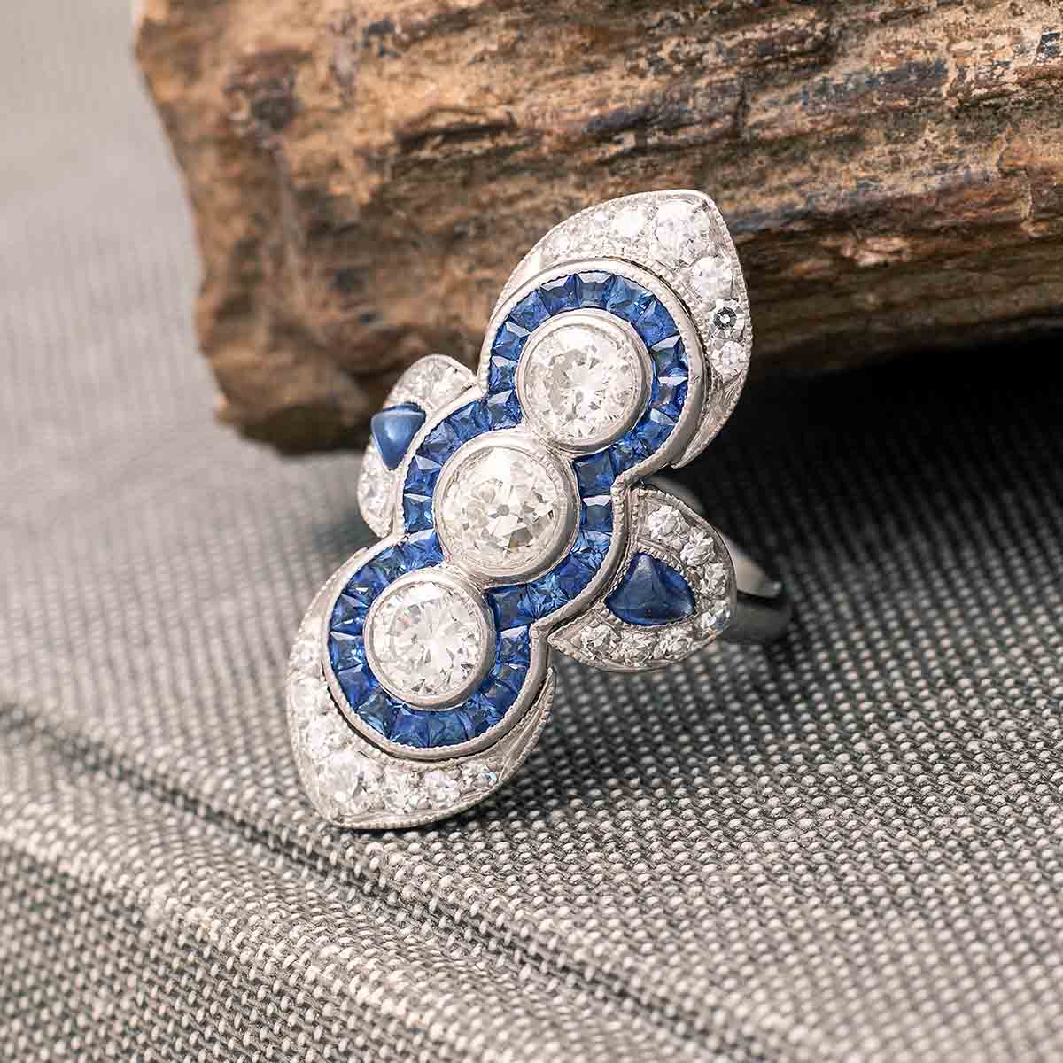 Art Deco Three Stones Diamond surrounded by calibrated Sapphire on Platinum Ring. Indian design inspiration as very often Art Deco period was influenced by various oriental cultures.